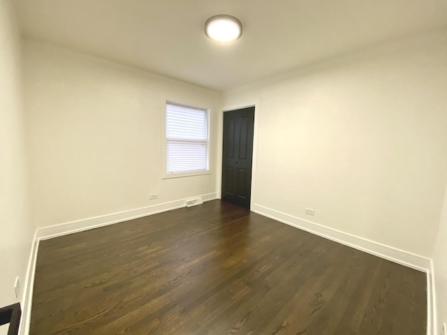 unfurnished room with dark wood finished floors and baseboards
