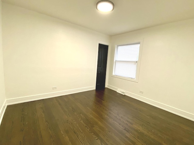 unfurnished room with baseboards and dark wood-style floors