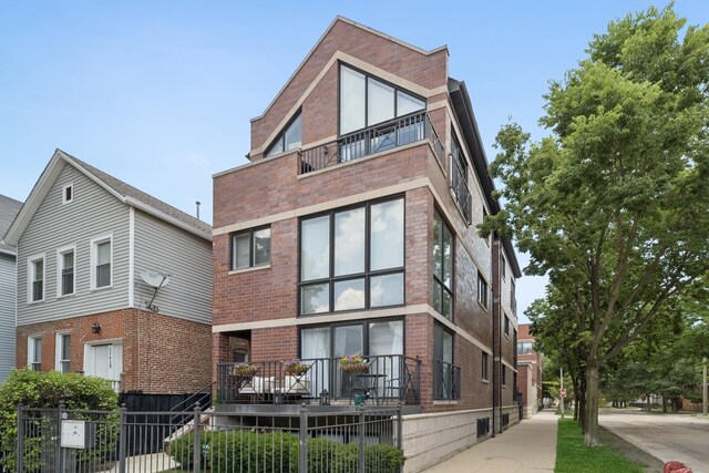 1701 N Washtenaw Ave Unit 1E, Chicago, IL 60647 - back of house featuring a balcony and brick siding