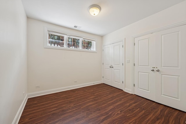 1701 N Washtenaw Ave Unit 1E, Chicago, IL 60647 - unfurnished bedroom featuring dark wood-style floors and two closets