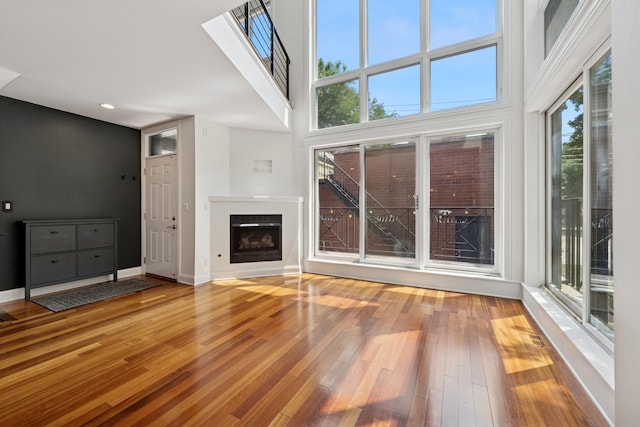 1701 N Washtenaw Ave Unit 1E, Chicago, IL 60647 - unfurnished living room with hardwood / wood-style flooring, a glass covered fireplace, recessed lighting, and a high ceiling