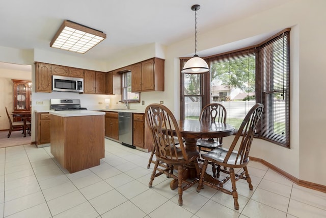 588 Montego Dr, Elk Grove Village, IL 60007 - kitchen with appliances with stainless steel finishes, a center island, light countertops, brown cabinetry, and decorative light fixtures