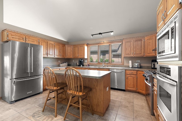 8542 Monaghan Dr, Tinley Park, IL 60487 - kitchen featuring stainless steel appliances, a center island, light tile patterned floors, a breakfast bar, and brown cabinetry