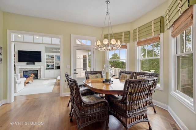6531 W Cedar Ct, Monee, IL 60449 - dining area with wood finished floors, a chandelier, and a glass covered fireplace