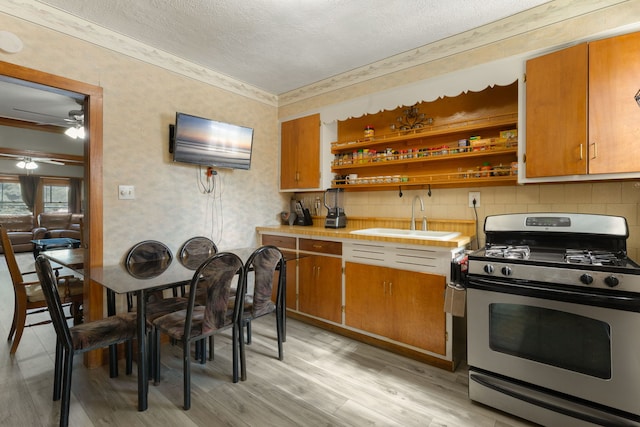 1314 Wesley Ave, Berwyn, IL 60402 - kitchen featuring gas stove, a textured ceiling, light wood finished floors, light countertops, and brown cabinetry