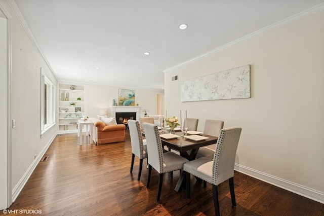 622 Kenilworth Ave, Kenilworth, IL 60043 - dining room with crown molding, dark wood-style flooring, a lit fireplace, recessed lighting, and built in features