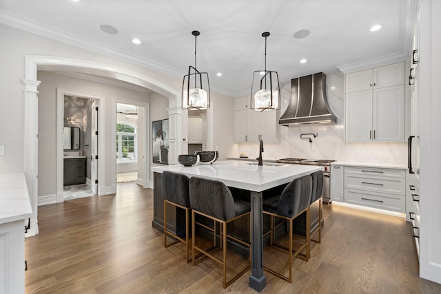 6403 S Garfield Ave, Burr Ridge, IL 60527 - kitchen featuring wall chimney range hood, stainless steel stove, arched walkways, white cabinetry, and dark wood finished floors