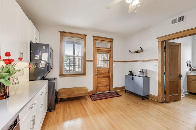 2333 N Spaulding Ave, Chicago, IL 60647 - kitchen featuring light wood-type flooring, white cabinetry, light countertops, estacked washer and dryer, and ceiling fan