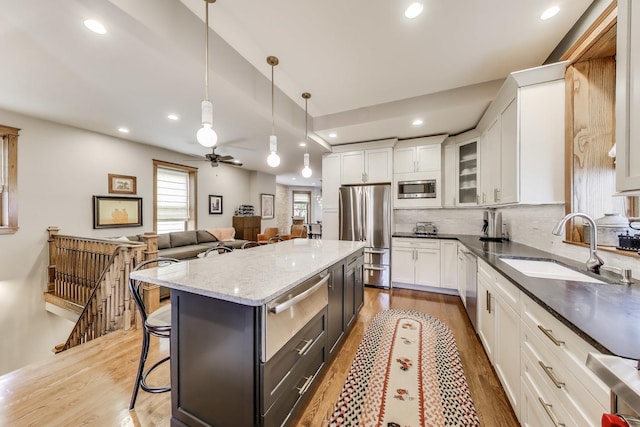 2333 N Spaulding Ave, Chicago, IL 60647 - kitchen with stainless steel appliances, white cabinets, light wood-type flooring, a breakfast bar, and a warming drawer