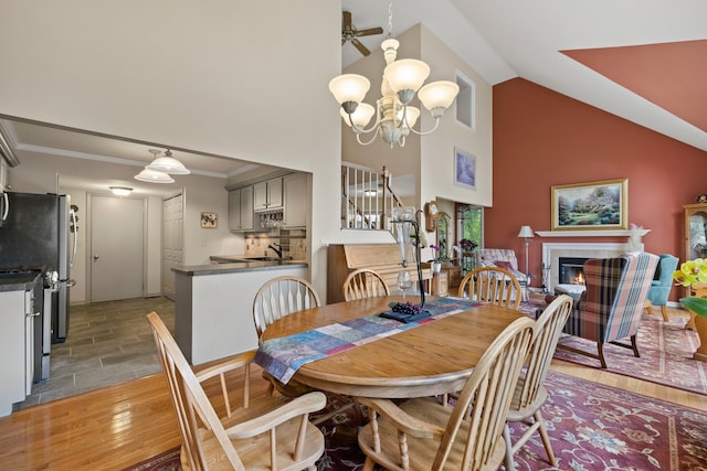 700 Monroe Dr, Lindenhurst, IL 60046 - dining space featuring a chandelier, a tile fireplace, high vaulted ceiling, ornamental molding, and stairway