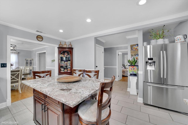 25 E 150th St, Harvey, IL 60426 - kitchen featuring stainless steel fridge with ice dispenser, light stone counters, a kitchen breakfast bar, recessed lighting, and a center island