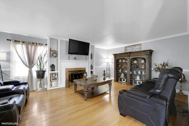 25 E 150th St, Harvey, IL 60426 - living area featuring light wood-style floors, a glass covered fireplace, crown molding, and built in shelves