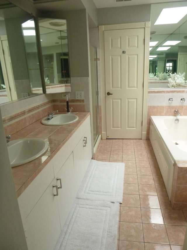 1027 W Vernon Park Pl Unit B, Chicago, IL 60607 - bathroom featuring tile patterned floors, double vanity, a bath, a shower stall, and a skylight