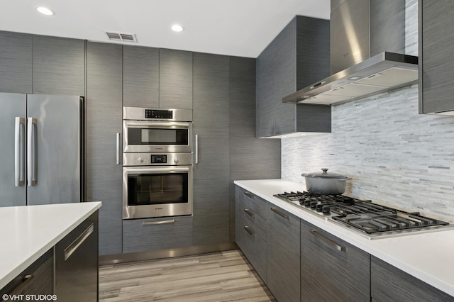 1018 N Larrabee St Unit 5S, Chicago, IL 60610 - kitchen featuring wall chimney range hood, stainless steel appliances, light countertops, light wood finished floors, and recessed lighting