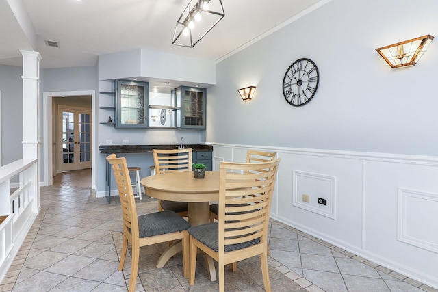 15442 W Purley Ct, Homer Glen, IL 60491 - dining area featuring light tile patterned flooring, ornate columns, wainscoting, a decorative wall, and crown molding
