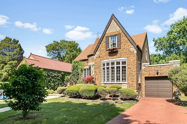 400 Selborne Rd, Riverside, IL 60546 - tudor-style house with a front yard, brick siding, an attached garage, and driveway