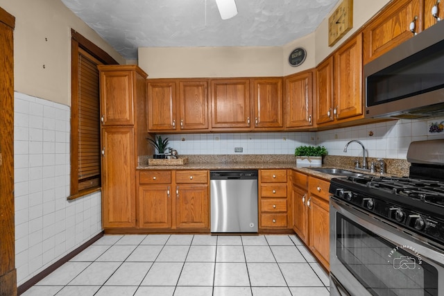 1246 N Monitor Ave, Chicago, IL 60651 - kitchen with stainless steel appliances, brown cabinets, light tile patterned floors, a textured ceiling, and tile walls