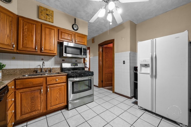 1246 N Monitor Ave, Chicago, IL 60651 - kitchen with appliances with stainless steel finishes, tile walls, a ceiling fan, brown cabinets, and light tile patterned floors