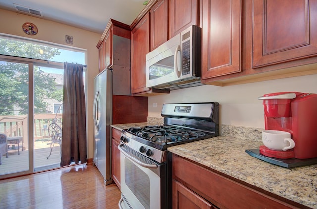 381 Chesapeake Ln, Oswego, IL 60543 - kitchen featuring appliances with stainless steel finishes, light wood-type flooring, light stone counters, and brown cabinetry