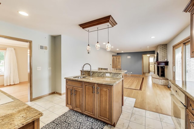 835 Tomawadee Ln, Park Ridge, IL 60068 - kitchen with an island with sink, brown cabinets, open floor plan, a fireplace, and light stone counters