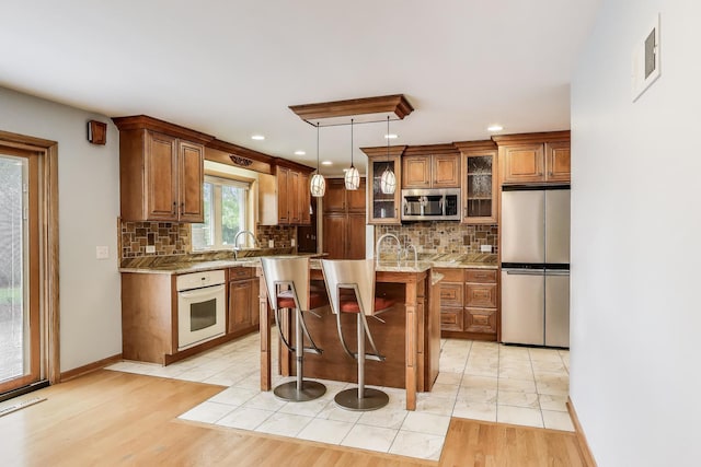 835 Tomawadee Ln, Park Ridge, IL 60068 - kitchen featuring stainless steel appliances, brown cabinets, a kitchen bar, tasteful backsplash, and recessed lighting
