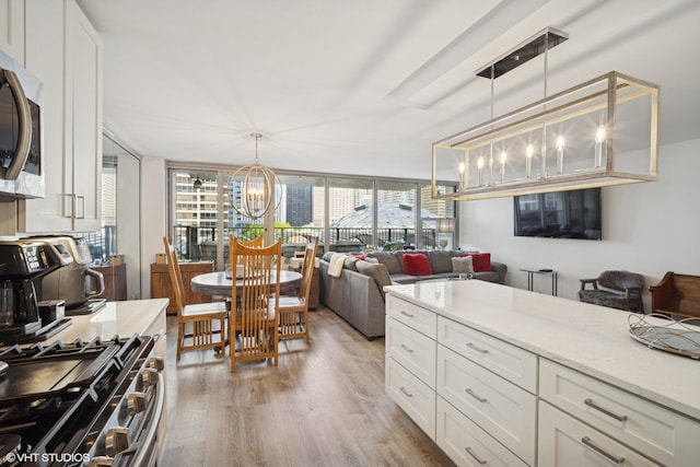 400 E Randolph St Unit 826, Chicago, IL 60601 - kitchen with a chandelier, appliances with stainless steel finishes, light wood-style floors, white cabinets, and light stone counters