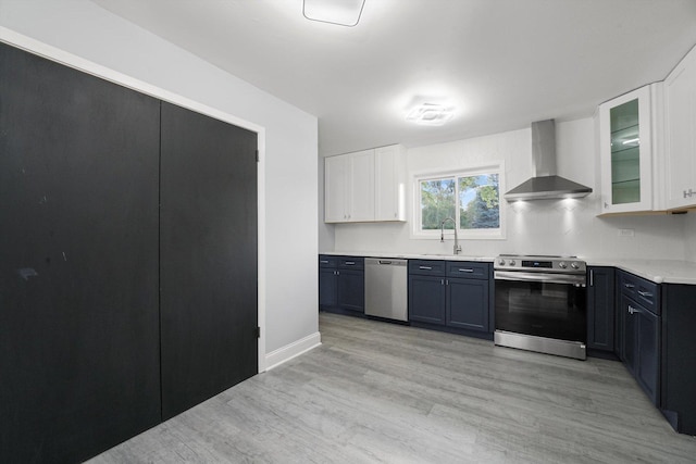 49 Stacy Ct, Glenview, IL 60025 - kitchen with stainless steel appliances, wall chimney exhaust hood, light wood-style flooring, white cabinets, and glass insert cabinets