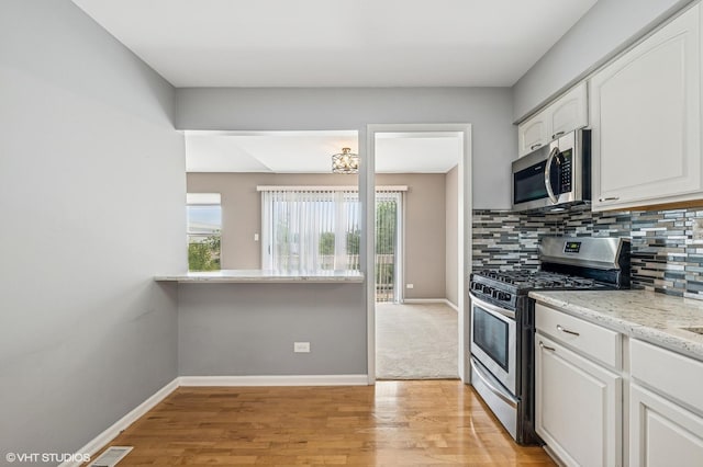 1234 Ballantrae Pl Unit D, Mundelein, IL 60060 - kitchen featuring stainless steel appliances, white cabinetry, light wood-type flooring, decorative backsplash, and light stone countertops