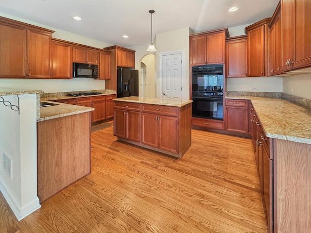 807 Wedgewood Ct, Lindenhurst, IL 60046 - kitchen featuring black appliances, arched walkways, light wood finished floors, brown cabinetry, and a kitchen island