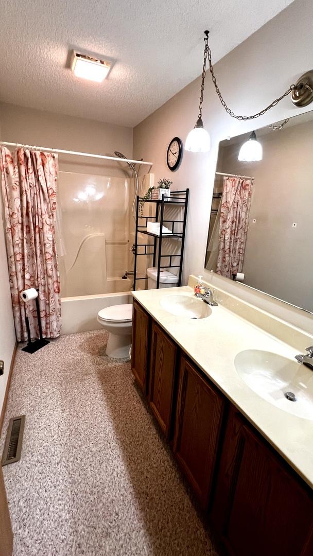 500 Jenkran Way Unit 2, Morrison, IL 61270 - full bathroom with shower / tub combo with curtain, double vanity, and a textured ceiling