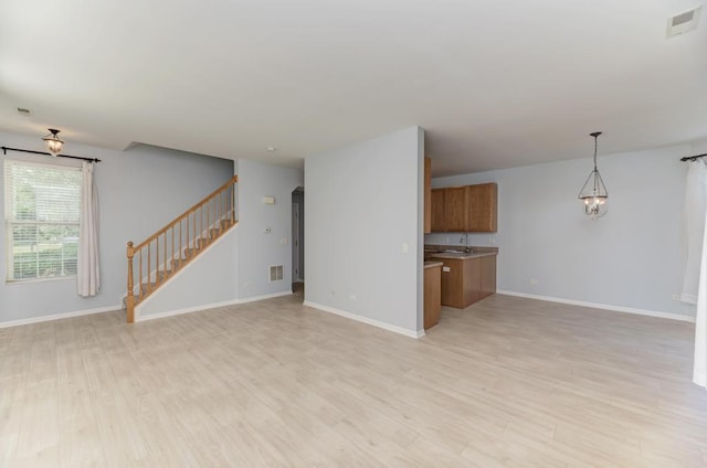 24341 Leski Ln, Plainfield, IL 60585 - unfurnished living room with light wood finished floors, stairs, and a chandelier