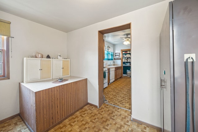2955 N Lotus Ave, Chicago, IL 60641 - kitchen with ceiling fan, light countertops, gas range gas stove, brown cabinetry, and fridge