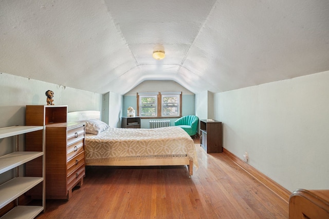 2955 N Lotus Ave, Chicago, IL 60641 - bedroom featuring radiator heating unit, wood-type flooring, vaulted ceiling, and a textured ceiling