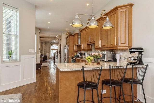 4456 S Berkeley Ave, Chicago, IL 60653 - kitchen featuring stainless steel appliances, a peninsula, a breakfast bar area, decorative backsplash, and dark wood-style floors