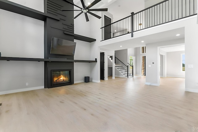 25216 S Channault Ave, Monee, IL 60449 - unfurnished living room with a large fireplace, wood finished floors, stairs, a high ceiling, and ceiling fan