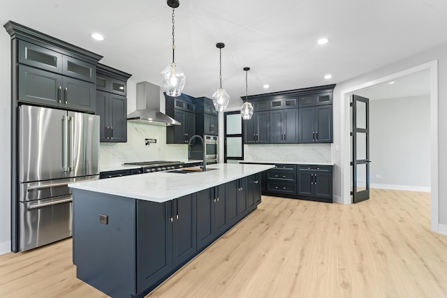 25216 S Channault Ave, Monee, IL 60449 - kitchen featuring stainless steel appliances, wall chimney exhaust hood, light wood-type flooring, tasteful backsplash, and a kitchen island with sink