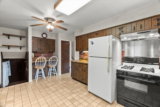 9160 S 88th Ct, Hickory Hills, IL 60457 - kitchen with gas stove, freestanding refrigerator, under cabinet range hood, ceiling fan, and light tile patterned floors