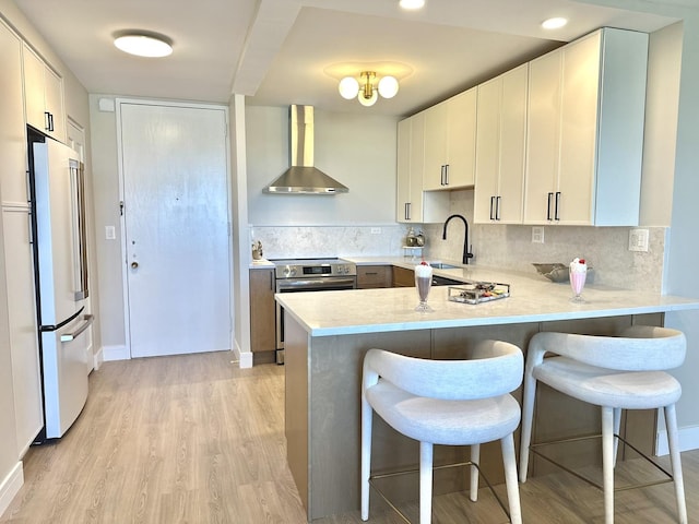 720 W Gordon Ter Unit 6J, Chicago, IL 60613 - kitchen featuring wall chimney exhaust hood, stainless steel electric stove, high end white fridge, a peninsula, and light wood finished floors