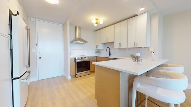 720 W Gordon Ter Unit 6J, Chicago, IL 60613 - kitchen with stainless steel electric range, wall chimney exhaust hood, freestanding refrigerator, a peninsula, and light wood-style floors
