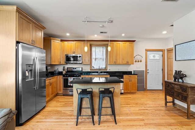 2222 Grey Ave, Evanston, IL 60201 - kitchen featuring appliances with stainless steel finishes, recessed lighting, dark countertops, light wood finished floors, and a breakfast bar