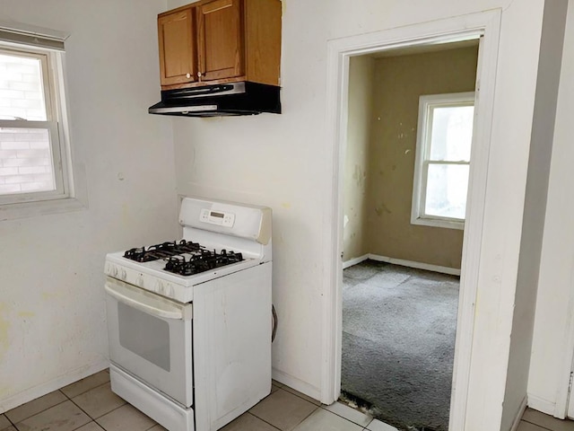 663 W 117th Pl, Chicago, IL 60628 - kitchen featuring white range with gas stovetop, under cabinet range hood, brown cabinets, light tile patterned floors, and light carpet
