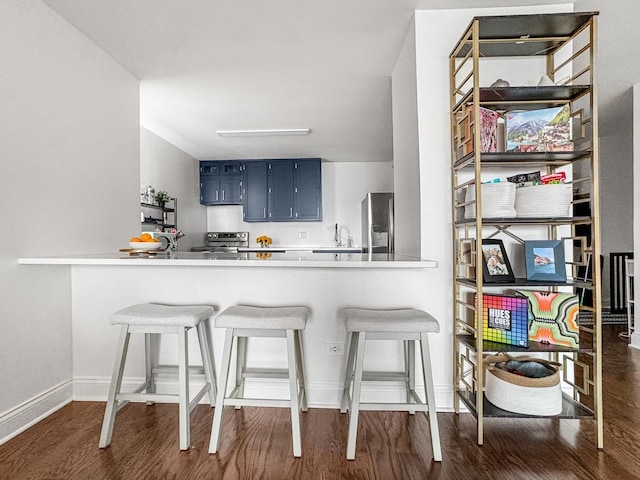 3150 N Sheridan Rd Unit 10C, Chicago, IL 60657 - kitchen featuring stainless steel appliances, dark wood-style floors, blue cabinets, a kitchen bar, and light countertops