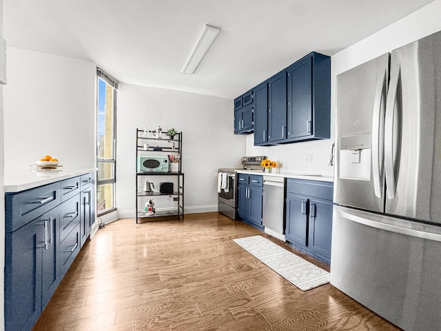 3150 N Sheridan Rd Unit 10C, Chicago, IL 60657 - kitchen with appliances with stainless steel finishes, plenty of natural light, blue cabinetry, and light wood-type flooring
