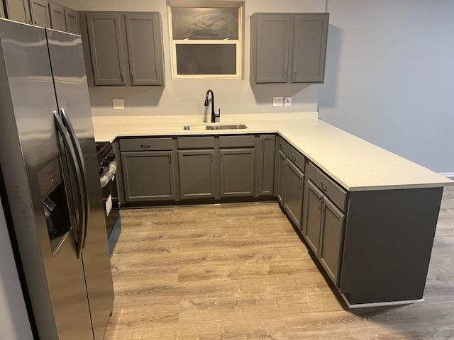 1352 S Kedvale Ave, Chicago, IL 60623 - kitchen with stainless steel fridge, light wood finished floors, gray cabinetry, and a peninsula