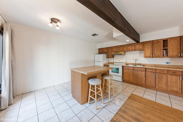 3341 Beacon St Unit 32, North Chicago, IL 60064 - kitchen with white appliances, under cabinet range hood, a kitchen island, a breakfast bar area, and light tile patterned floors