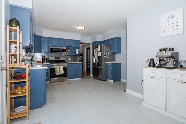 3308 Cumbria Dr, Bloomington, IL 61704 - kitchen featuring blue cabinetry, appliances with stainless steel finishes, light countertops, tasteful backsplash, and a textured ceiling