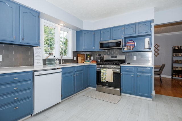 3308 Cumbria Dr, Bloomington, IL 61704 - kitchen with stainless steel appliances, blue cabinets, light countertops, and tasteful backsplash