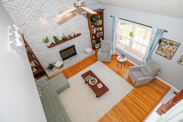 3308 Cumbria Dr, Bloomington, IL 61704 - living room with wood finished floors, a ceiling fan, a fireplace, vaulted ceiling, and a textured ceiling