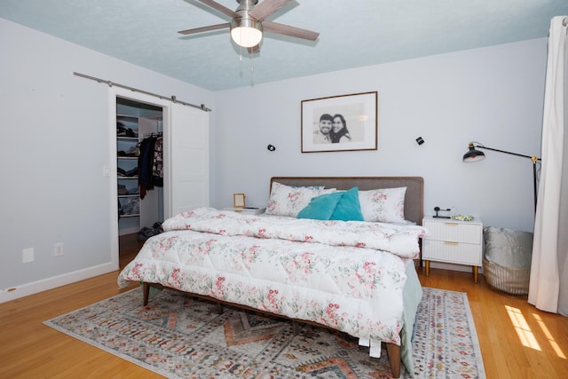 3308 Cumbria Dr, Bloomington, IL 61704 - bedroom with a barn door, wood finished floors, a spacious closet, and a ceiling fan