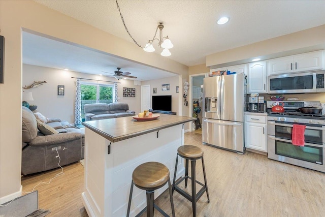 505 Tamula Dr, Mahomet, IL 61853 - kitchen featuring appliances with stainless steel finishes, open floor plan, white cabinetry, light wood-style flooring, and a center island
